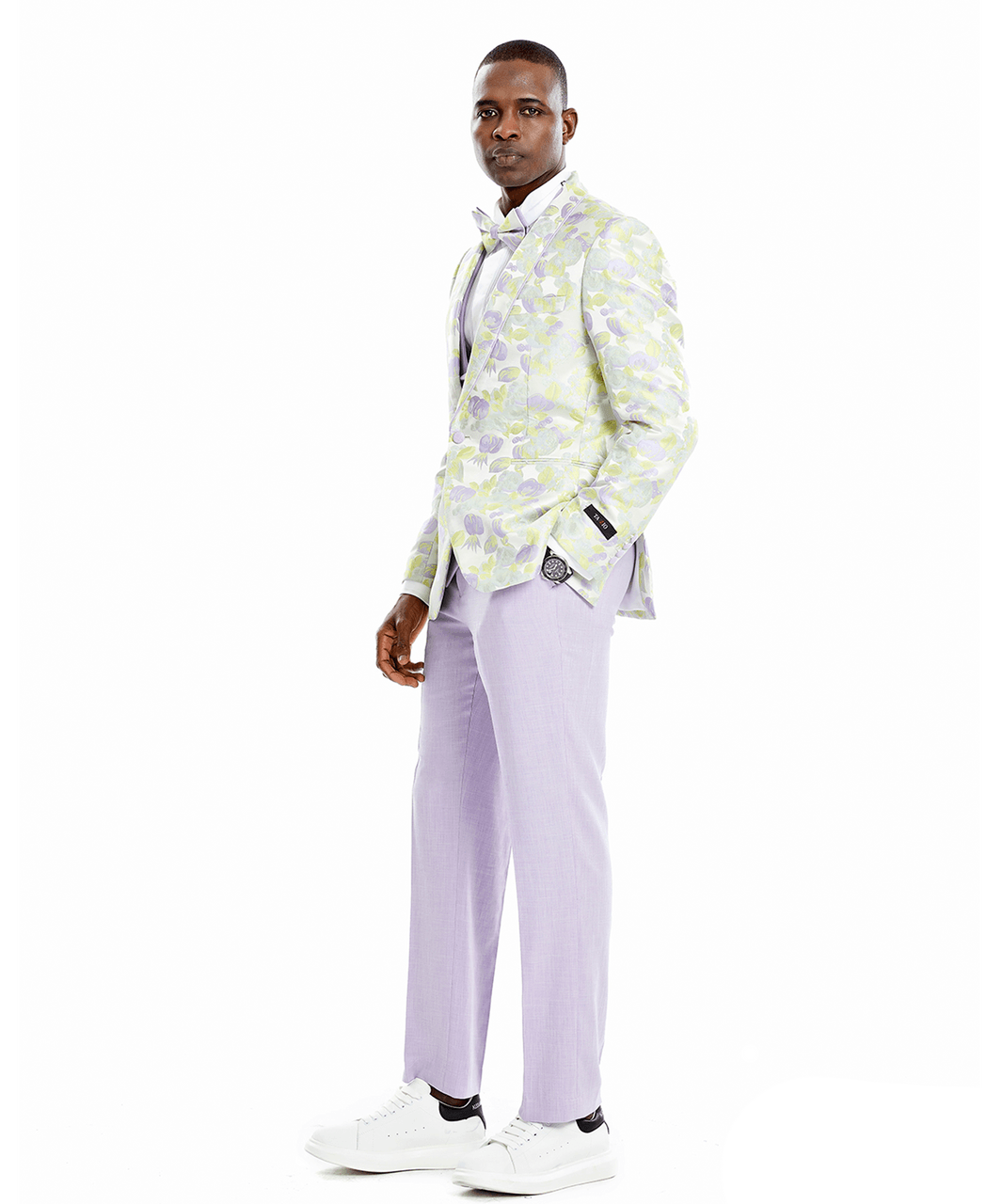 A man wearing a 3-piece suit. Floral patterned jacket, solid colored vest and pants. Bowtie matches floral jacket.