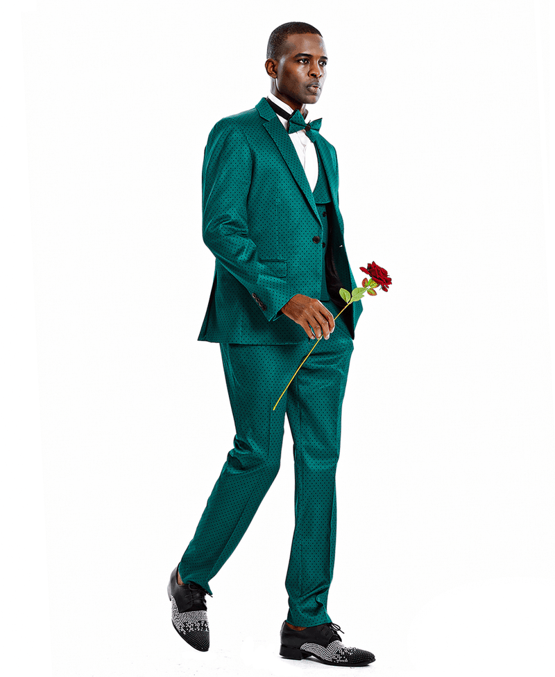 A man wearing a green suit with black polka-dots and a matching bowtie. 3-piece suit with a double-breasted vest. Holding a rose.